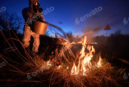 Preview: Fireman ecologist extinguishing fire in field in the evening