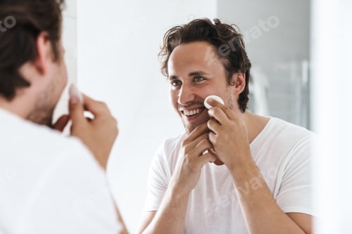 Preview: Attractive young man standing in front of the bathroom mirror