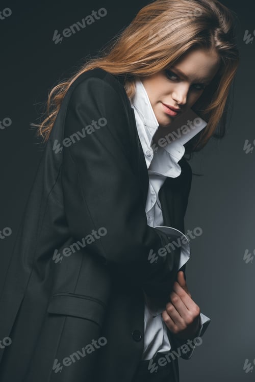 Preview: Young adult woman posing in male costume on black background, studio shot