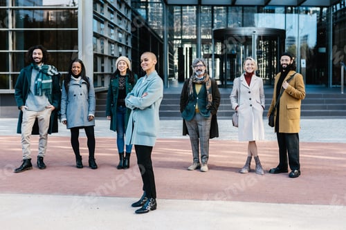 Preview: Successful mid adult businesswoman standing with business colleagues outdoors.