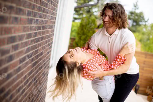 Preview: Smiling young couple in love in front of house brick wall