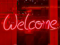 Preview: Closeup of red welcome neon sign hanging on the window of bar or night club