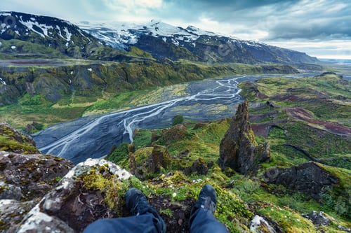 Preview: Boots of hiker sitting on the cliff surrounded by volcanic mountain in Thorsmork