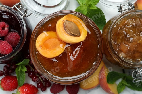 Preview: Jars with different jams and fresh fruits on white table, flat lay