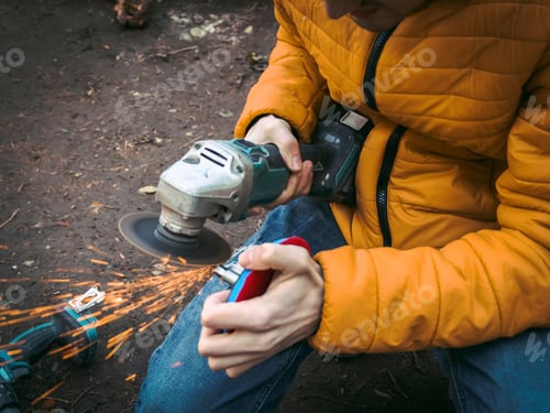 Preview: A young caucasian man in a yellow jacket is holding a drill in his hands and polishing a disc