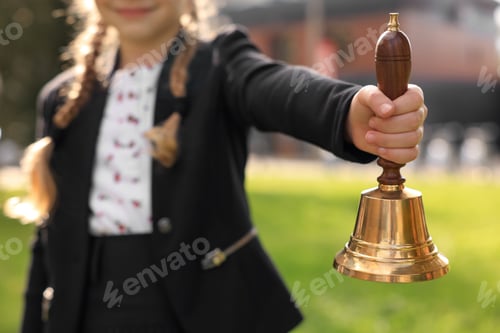 Preview: Closeup view of pupil holding school bell outdoors on sunny day