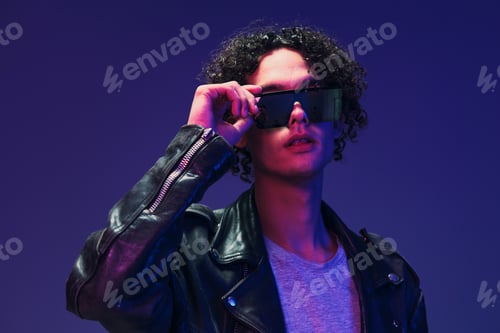 Preview: Attractive curly man leather jacket wear mirror glasses looks at camera posing isolated on color