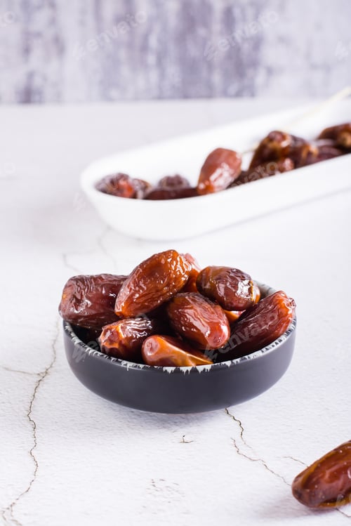 Preview: Ripe dried dates in a bowl on the table. Oriental dessert. Vertical view