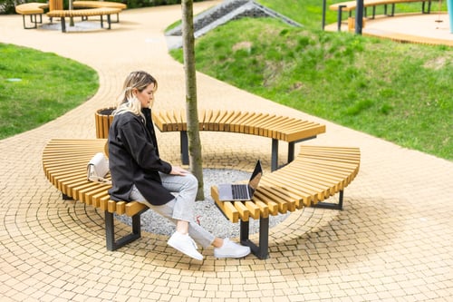 Preview: Young beautiful business woman sitting on a bench in the sunny city