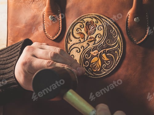 Preview: hands of unrecognizable leather craftsman working on measurements patterns in local workshop studio