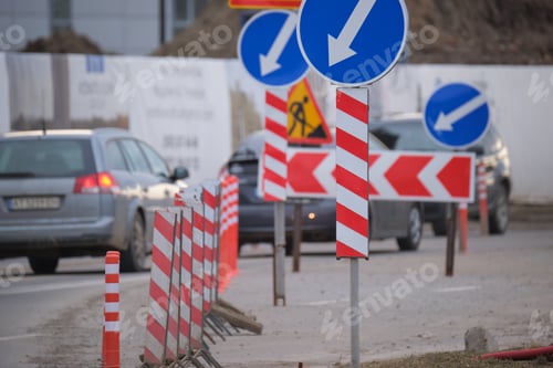 Preview: Roadworks warning traffic signs of construction work on city street and slowly moving cars
