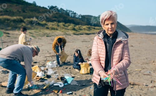 Preview: Woman showing handful of straws collected on the beach
