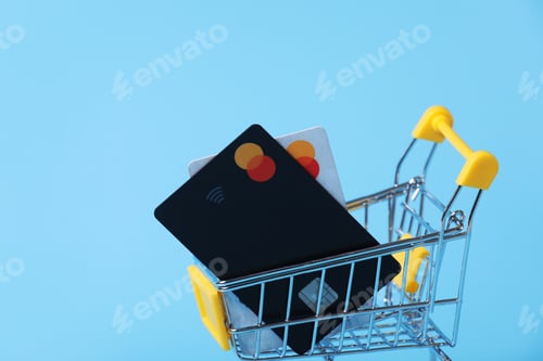 Preview: credit cards in shopping cart isolated on a blue background. close-up of shopping trolley. Purchasin