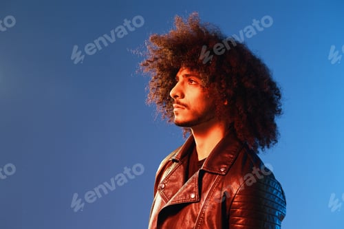 Preview: Portrait of a stylish man with curly hair with glasses smile on blue background multinational, color