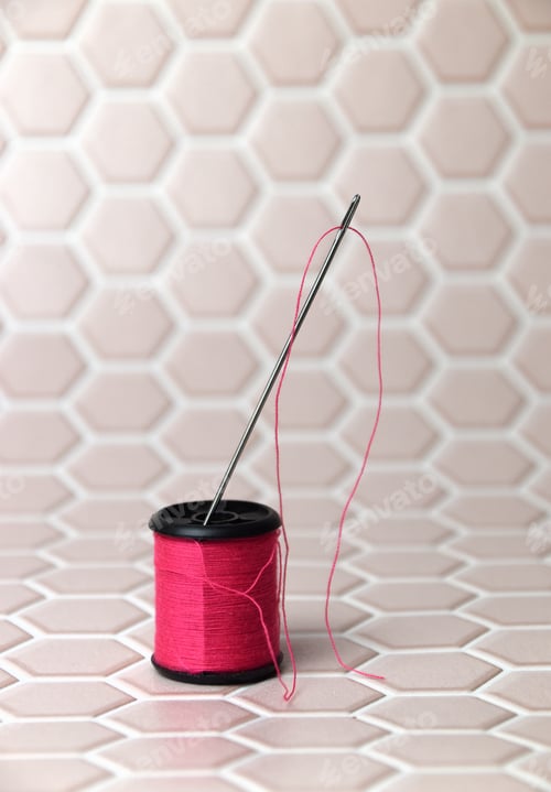 Preview: pink thread and a needle on pale pink background
