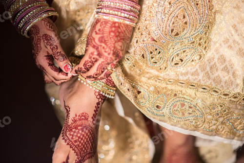 Preview: Female with henna tattoos putting on a leg bracelet