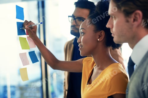 Preview: Cropped shot of a group of businesspeople brainstorming with notes on a glass wall in an office