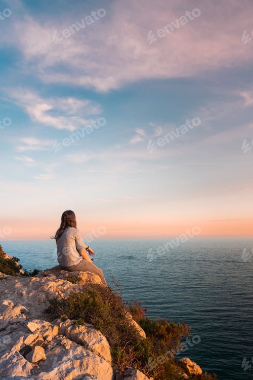 Preview: Young woman watching the sea during sunset