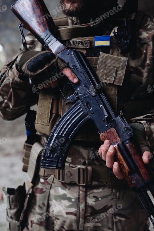 Preview: A soldier is holding an assault rifle, close-up.