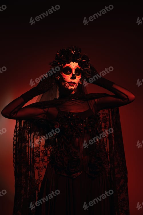 Preview: Woman in black costume and santa muerte makeup touching black wreath on burgundy background with red