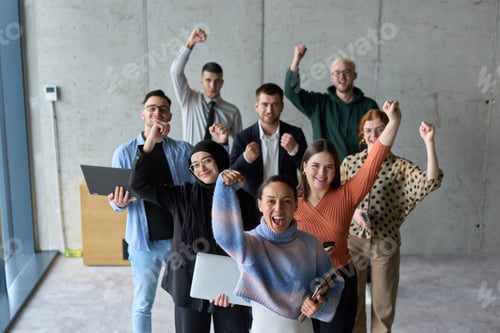 Preview: A diverse team of business professionals ecstatically celebrating their success in a modern office