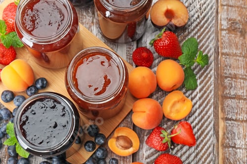 Preview: Different jams in jars and ingredients on wooden table, flat lay
