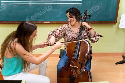 Preview: Music teacher helping student playing cello in classroom