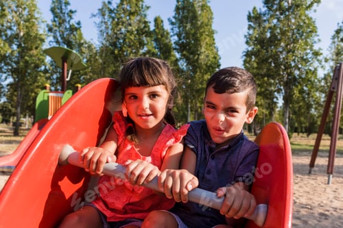 Preview: Two kids having fun playing together on a playground in a park.