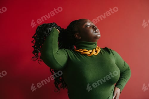 Preview: Confident plus size African woman adjusting her braided hair and keeping eyes closed