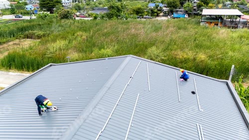 Preview: Men technicians mounting photovoltaic solar moduls on rooftop of warehouse.