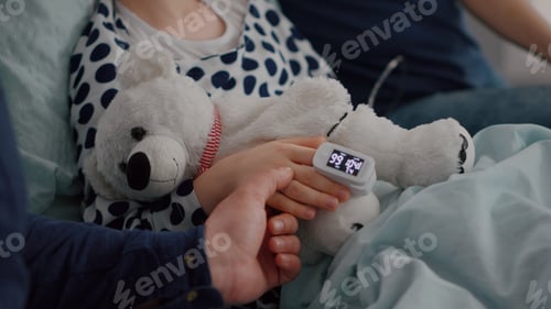 Preview: Close up of sick daughter resting in bed with medical oximeter on finger