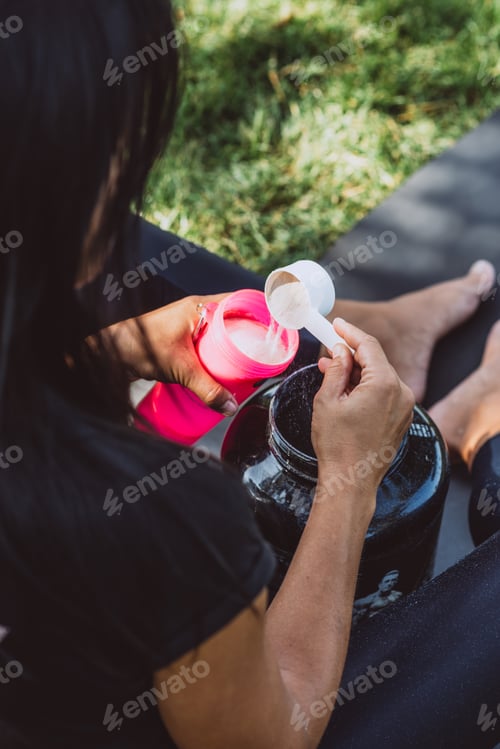 Preview: sport, fitness, healthy lifestyle - a woman with a can and a bottle preparing a protein shake