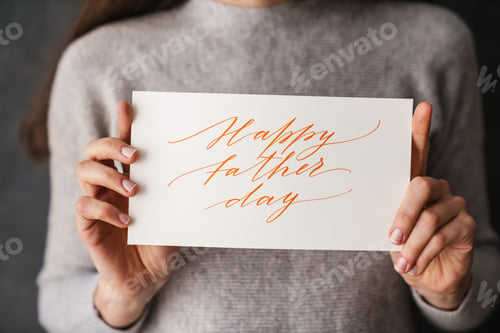 Preview: Caucasian girl showing happy father day card at camera