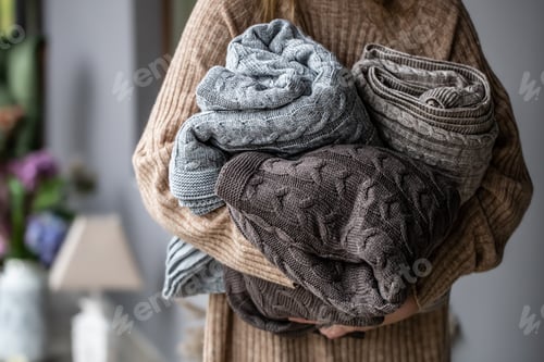 Preview: Warm knitted blankets in pastel colors in women's hands.