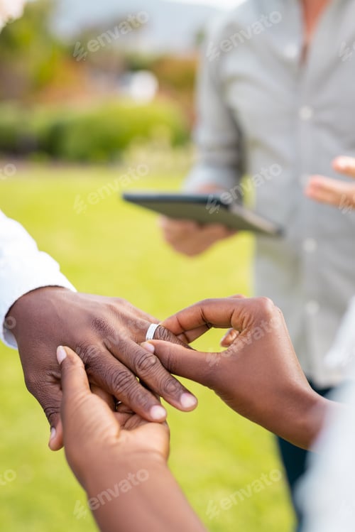 Preview: Close up of african american couple holding hands and putting ring during wedding