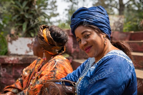Preview: Portrait of a smiling African lady dressed in traditional clothes next to a friend.