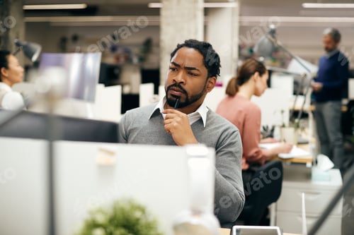 Preview: Pensive black businessman working on desktop PC at corporate office.