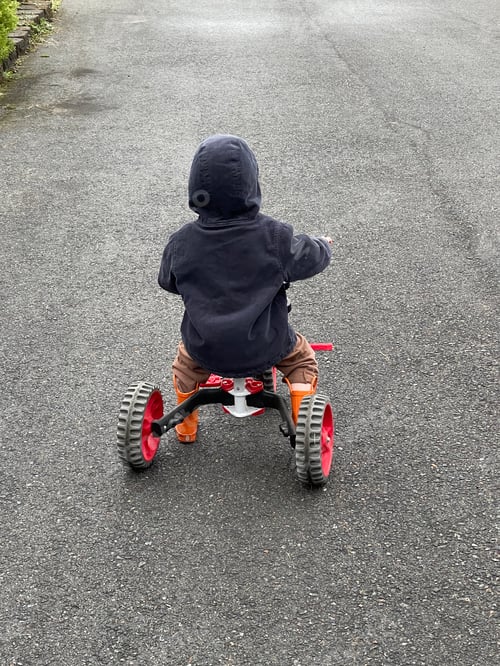 Preview: A Young Boy Rides a Tricycle on the Road on a Brisk Morning