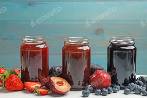Preview: Different sweet jams in jars and ingredients on white table