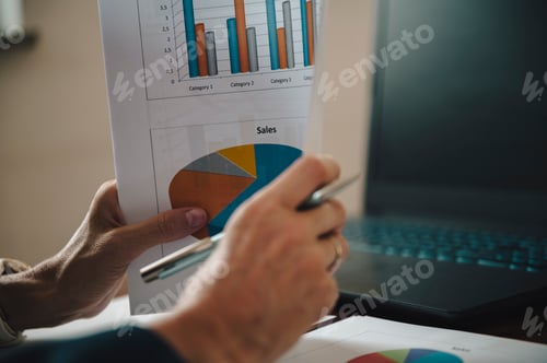 Preview: Hands of a businesswoman holding financial plan or report with statistical graphs