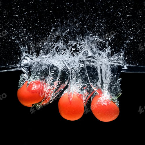 Preview: close up view of ripe tomatoes falling into water isolated on black