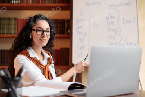 Preview: English teacher sitting at desk, explaining lesson to students