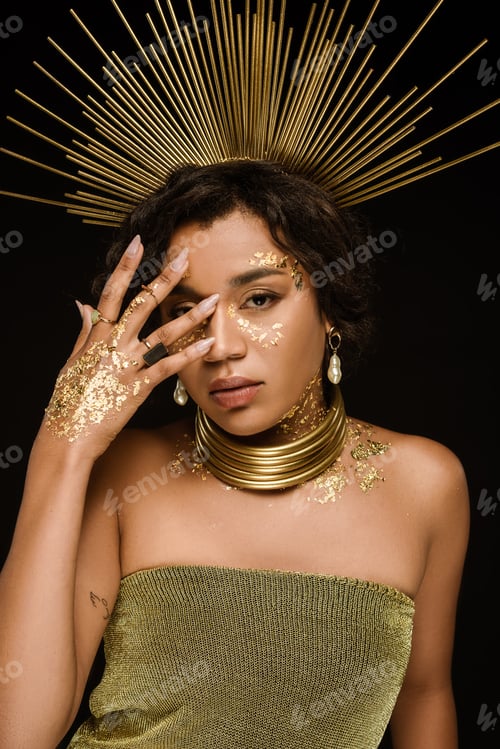 Preview: brunette african american woman with golden accessories and paint on face posing isolated on black