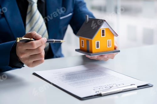 Preview: Real estate agent home sales broker is using a pen pointing to the house model and explains the busi