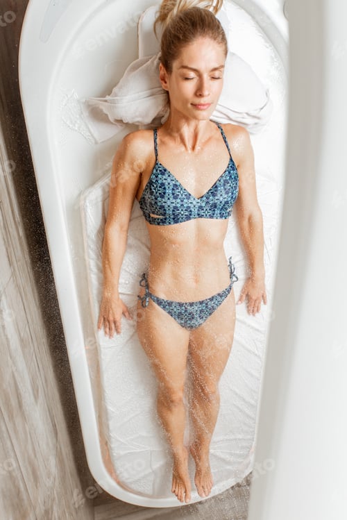Preview: Woman lying under the hot shower in the spa