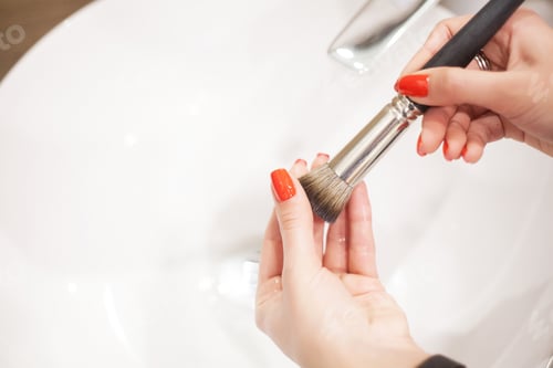 Preview: Makr up brush. Woman washing dirty makeup brush with soap and foam in the sink