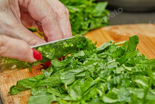 Preview: Chef cuts basil according to the recipe for cooking on wooden board in the kitchen
