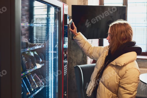 Preview: Woman paying for product at vending machine using contactless method of payment with mobile phone