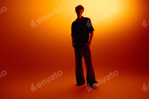 Preview: Stylish young man posing confidently against a vibrant orange backdrop