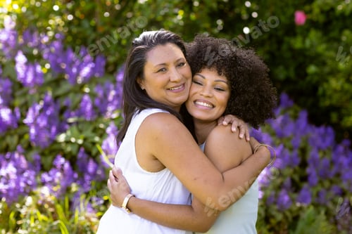 Preview: Mother and Daughter, mature biracial woman and young biracial woman hugging in garden at home